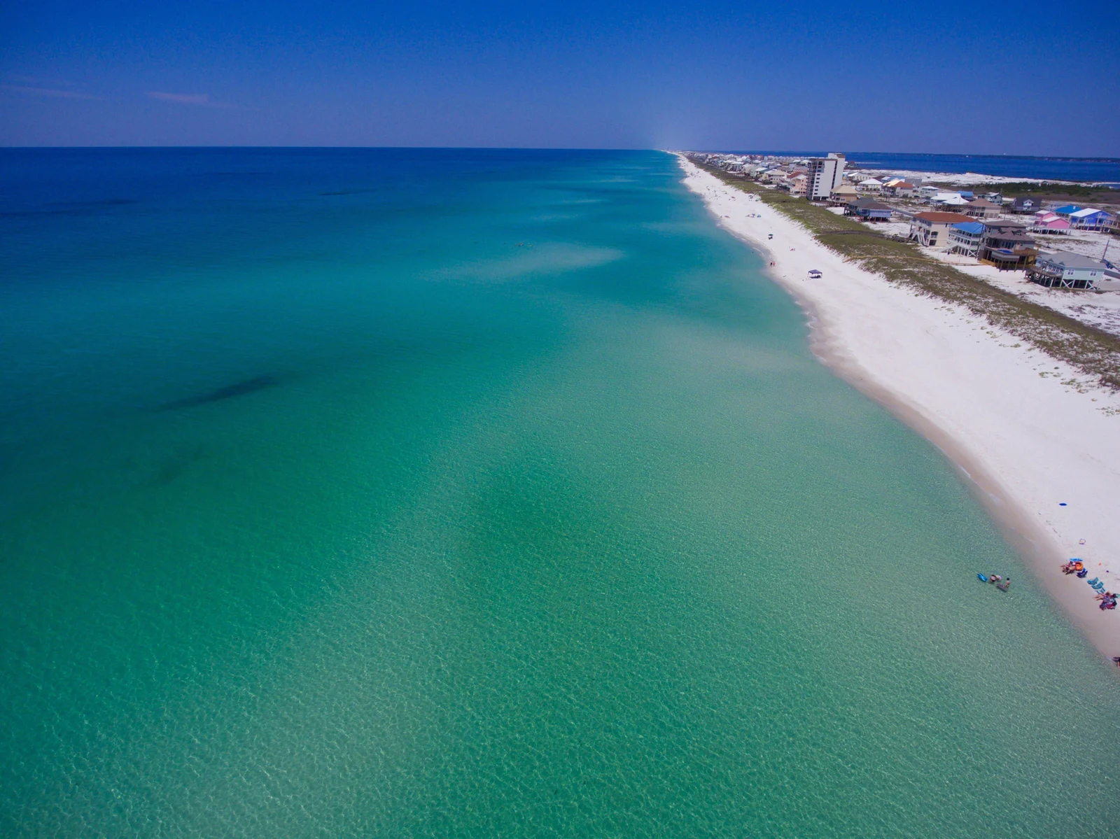 Aerial view of the Emerald Coast — white sand beaches and turquoise Gulf water along the Pensacola Beach and Perdido Key shoreline