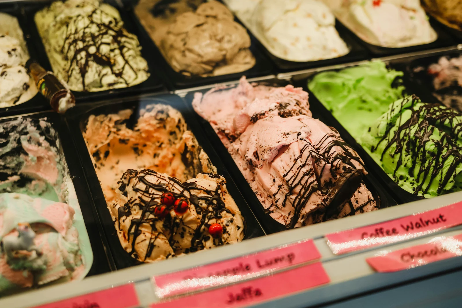 A display case of artisan ice cream in multiple flavors including chocolate, strawberry, and pistachio