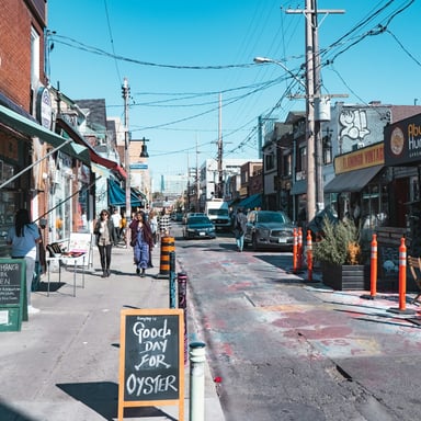 Sunny neighborhood street with local shops and an oyster chalkboard sign