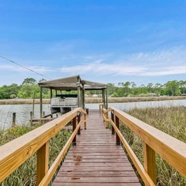 Wooden dock leading to a covered boat slip on a calm bayou